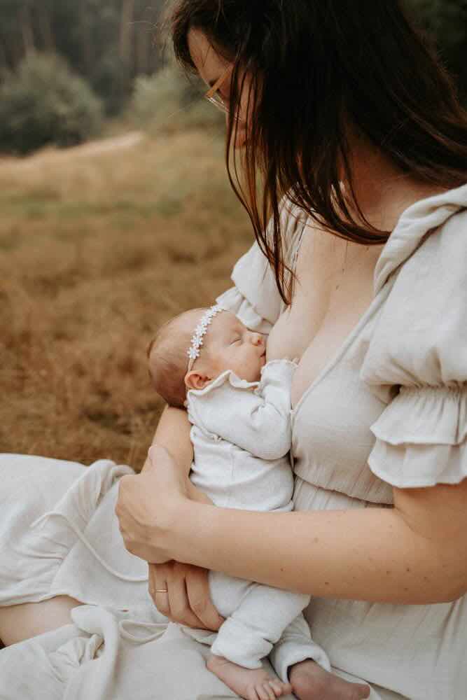 Moeder met haar pasgeboren baby bij een raam in een warme, rustige setting