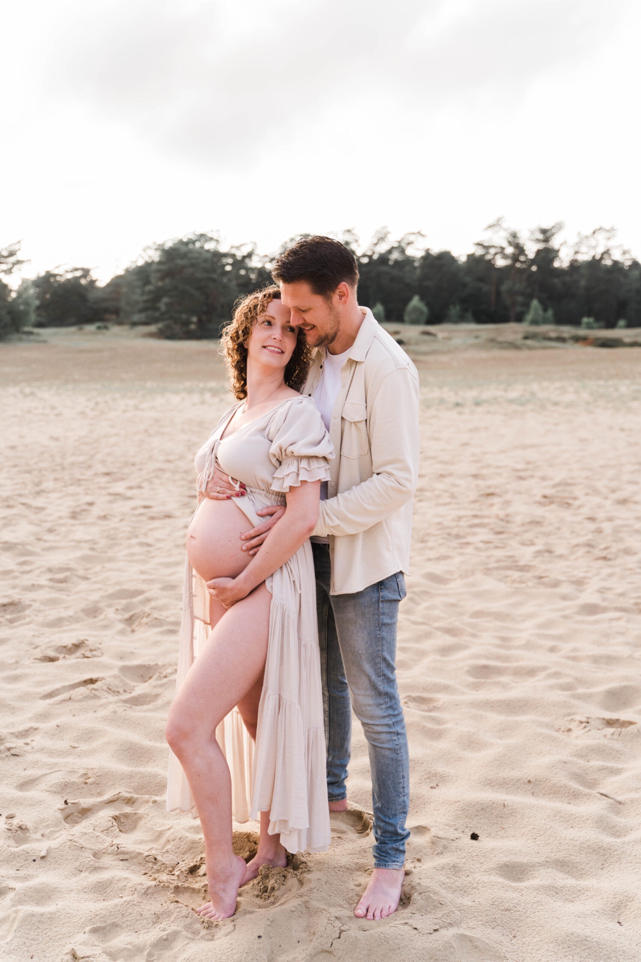 Zwangerschapsfoto van een stel in een zandlandschap