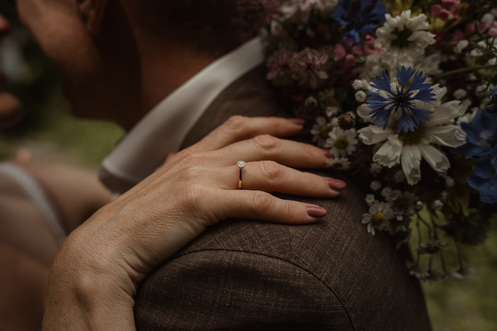 Detailfoto van verlovingsring op de schouder van de bruidegom