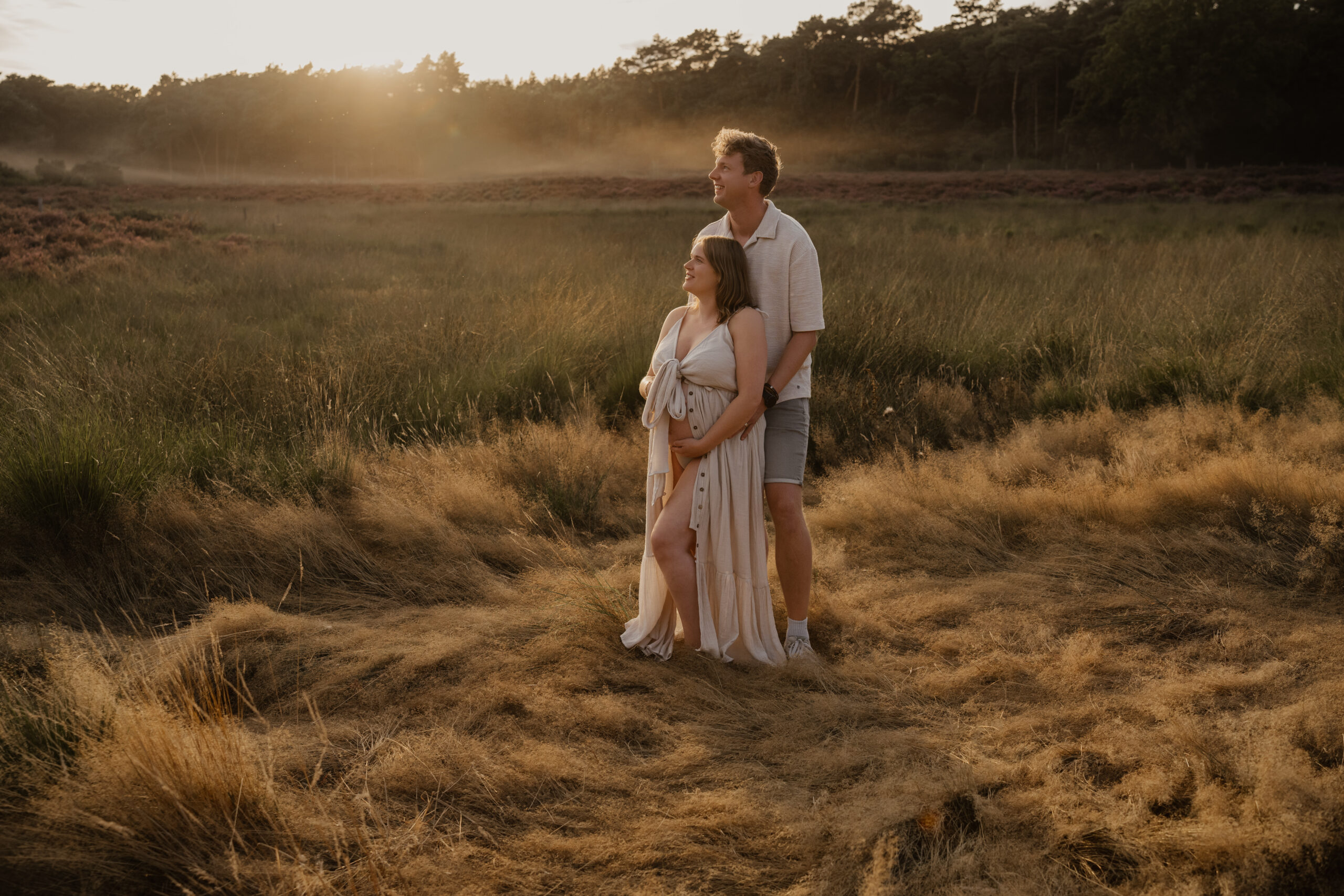 Zwanger stel op de heide bij zonsondergang tijdens een zwangerschapsshoot in de Achterhoek